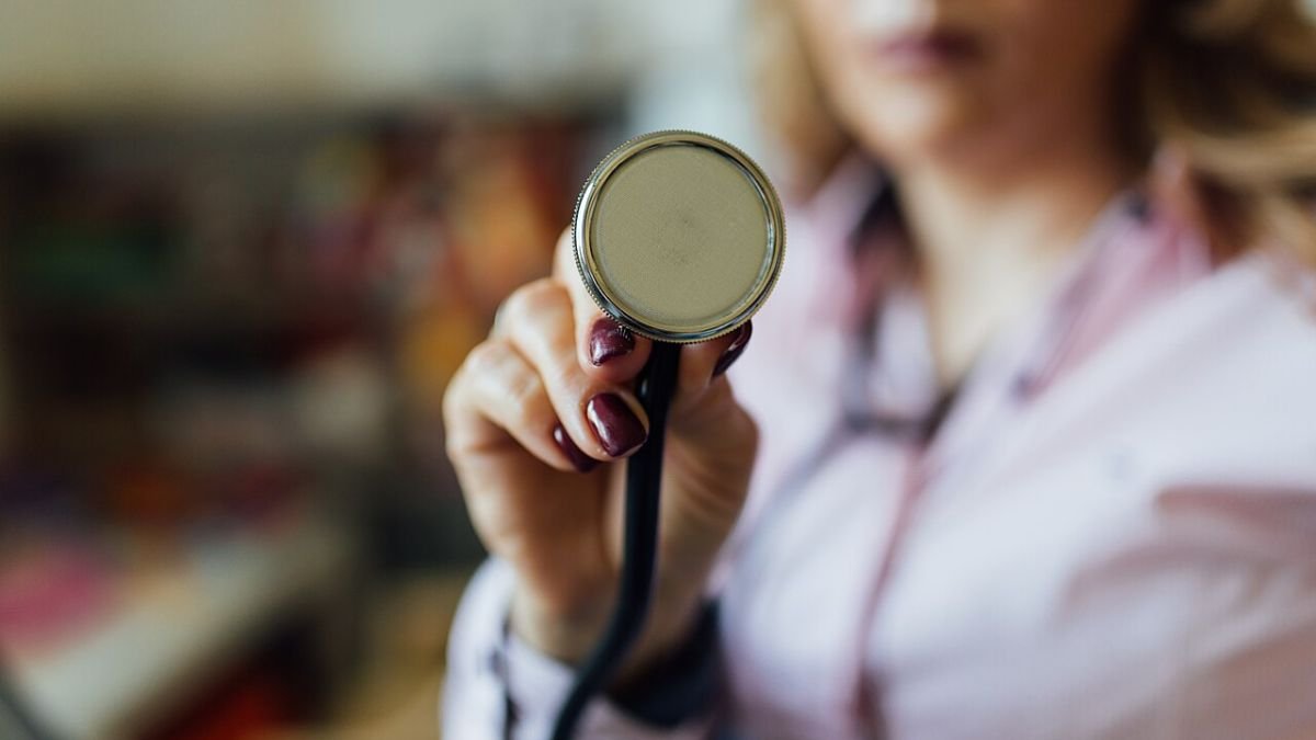 A doctor holding the chest piece of a stethoscope