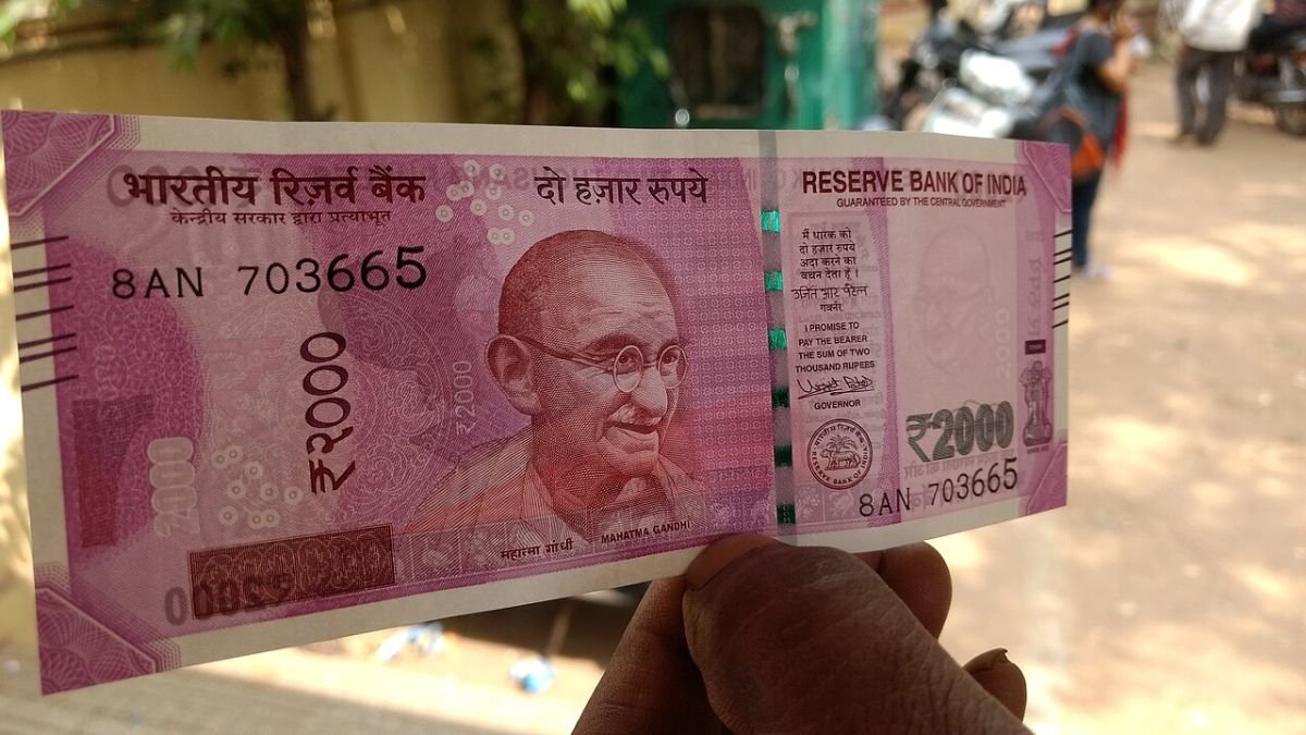 A hand holding an Indian rupee note